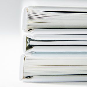 A large stack of documents organized on top of a white desk.