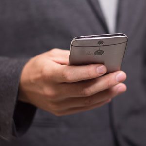 A business man holding a phone and sending an important text message.