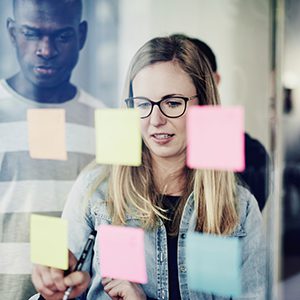 The manager is showing the associate some of the key notes she took during the meeting that she wrote on post-its.