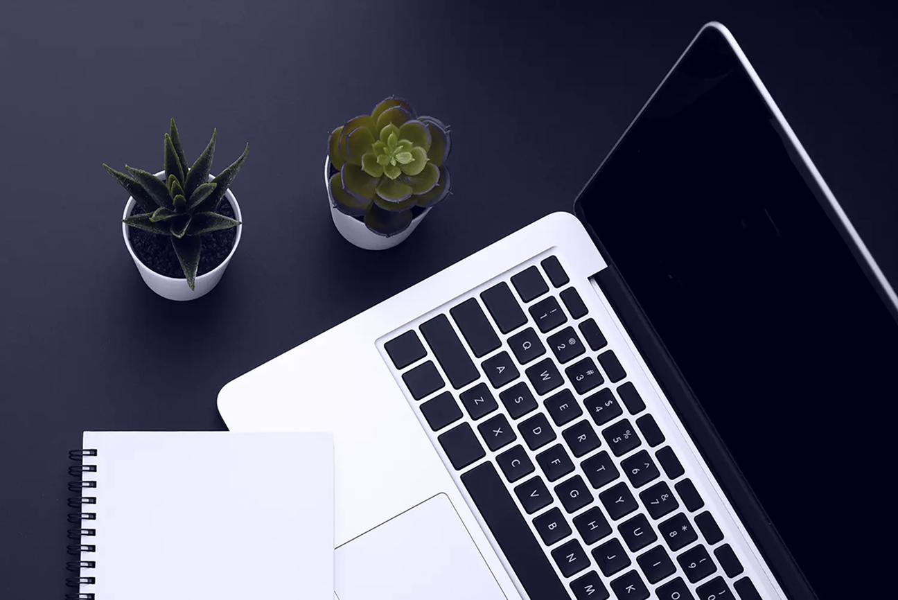 A minimalist, high-angle flat lay of a workspace on a dark, matte surface.